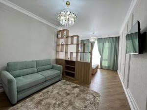 sala de estar con sofá y estante para libros en Здесь вы ощутите себя как дома, en Almaty