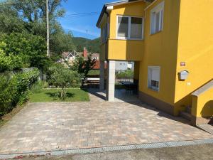 a yellow house with a brick walkway next to it at Apartma Mira in Zgornje Škofije +3 photos