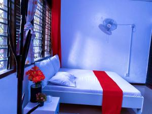 a bedroom with a white bed with a red blanket at Tinas Royal Cottage in Mombasa