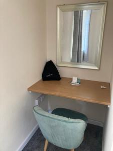 a bathroom with a mirror and a blue chair at Ashes Farm Cottage in Kilmington