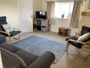 a living room with a couch and chairs and a tv at Ashes Farm Cottage in Kilmington