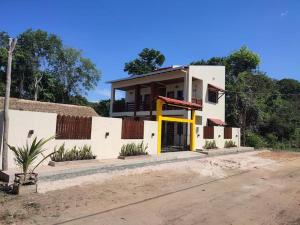 ein weißes Haus mit gelber Tür auf einer Straße in der Unterkunft Casa em Alter do Chão - Nosso Canto in Santarém