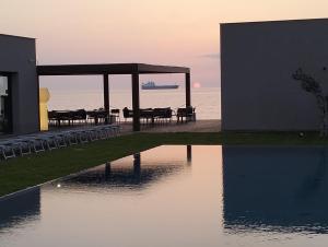 a building with tables and chairs next to a body of water at Hotel Punta Tipa in Trapani