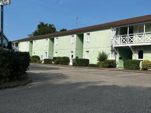 a large building with a parking lot in front of it at Hôtel Gex in Gex