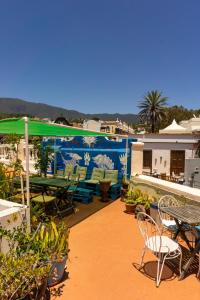 eine Terrasse mit Stühlen, einem Tisch und einem Sonnenschirm in der Unterkunft Hostel Albergue La Casa Encantada in El Paso
