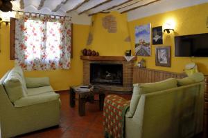 a living room with two chairs and a fireplace at Casa Rural La Tahona in Elche de la Sierra
