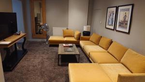 a living room with yellow couches and a tv at Salzachblick in Salzburg