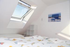 a white bedroom with a bed with a window at FeWo Bayha "Im blauen Haus" in Langenargen