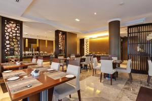 a restaurant with wooden tables and white chairs at Icon Delux Hotel Apartments Al Barsha - Formerly Abidos in Dubai