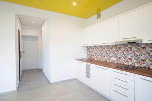 a kitchen with white cabinets and a tile wall at Studio Świętojańska in Gdynia