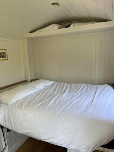 Ce lit se trouve dans un dortoir doté de draps blancs. dans l'établissement Robins Retreat - orchard with hot tub - see extras, à Alfriston