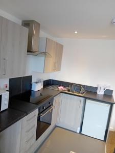 una cocina con armarios blancos y encimeras negras en Windies apartment 3, en Bridlington