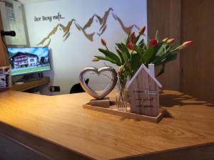 un trofeo di cuore e un vaso di fiori su una scrivania di Hotel Restaurant Liesele Sonne a Sankt Leonhard im Pitztal