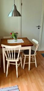 a wooden table with two chairs and a vase of flowers on it at Havsnärastugan in Öckerö