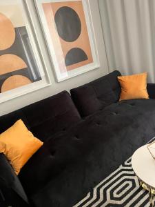 un sofá negro con almohadas naranjas en la sala de estar. en Apartament Solny Resort A032 z klimatyzacją, en Kołobrzeg