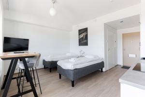 a room with two beds and a tv and a desk at Serviced Apartments Pirkkala by UHANDA in Tampere
