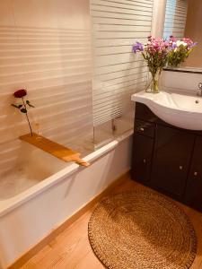 La salle de bains est pourvue d'un lavabo et d'une baignoire fleurie. dans l'établissement Les rives de l’Indre. Parking gratuit. Lit 160CM, à Châteauroux