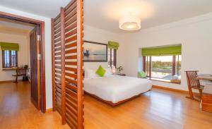 a bedroom with a bed and a room with a table at Elites Riverside Hotel & Spa Hoi An in Hoi An