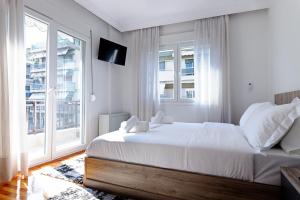- une chambre blanche avec un lit et une grande fenêtre dans l'établissement Marilians Luxury Apartment, à Thessalonique