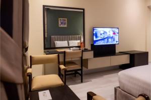 a hotel room with a television and a bed at Capital O 126 Manama Tower Hotel in Manama