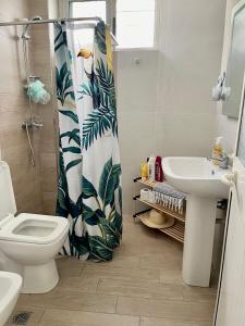 a bathroom with a shower curtain with a toilet and a sink at Lola’s Apartment in Durrës