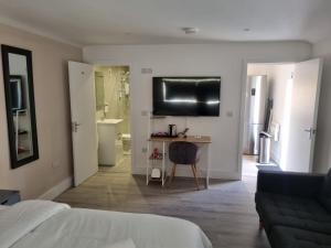 a bedroom with a bed and a desk and a bathroom at The Coppice-Private Studio Guest Suite With Private Entrance in Watford