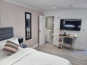 a bedroom with a bed and a desk with a television at The Coppice-Private Studio Guest Suite With Private Entrance in Watford