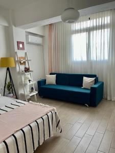 a living room with a blue couch and a window at Lola’s Apartment in Durrës