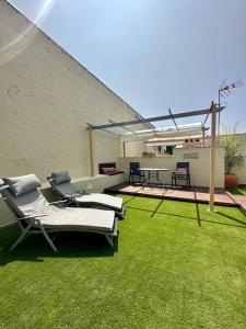 a patio with lawn chairs and a table on a building at La Casa de la Alameda in Málaga