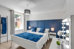 une chambre avec un grand lit et une tête de lit bleue dans l'établissement Sleeps 8 City House with Cinema Room and Parking, à Norwich