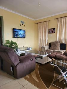 - un salon avec un canapé, une table et des chaises dans l'établissement G&G Westindies Executive One Bedroom, à Eldoret