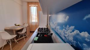 een keuken met een blauwe muur met wolken erop geschilderd bij Ale's By The Sea in Mamaia Nord – Năvodari