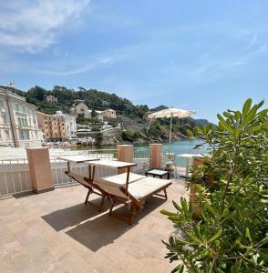 un patio con mesa, bancos y agua en Hotel Miramare & Spa, en Sestri Levante