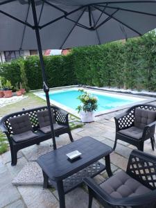 un patio con 2 sillas y una sombrilla junto a la piscina en Villa Celeste en Murazzo