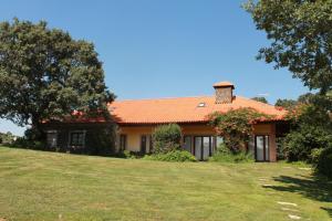 uma casa com um telhado laranja num campo de relva em Quinta do Adil em Macedo de Cavaleiros