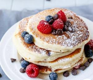 a stack of pancakes with berries on a plate at Onar Mani Suites in Neon Oitilon
