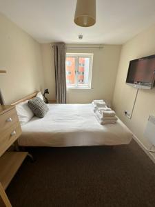 a bedroom with a bed with a tv on the wall at Gunwharf Quays Harbour Apartments in Portsmouth
