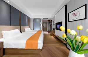 ein Hotelzimmer mit einem Bett und einer Vase aus gelben Blumen in der Unterkunft Morninginn, Qingyuan Gulong Gorge Wanda Plaza in Qingyuan