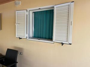- deux fenêtres dans une pièce avec une chaise et un rideau vert dans l'établissement Chania Casa Portokali, à Perivólia