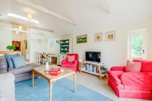 a living room with two red chairs and a table at Thyme Cottage in Eastdean