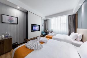 ein Hotelzimmer mit 2 Betten und einem Flachbild-TV in der Unterkunft Morninginn, Qingyuan Gulong Gorge Wanda Plaza in Qingyuan