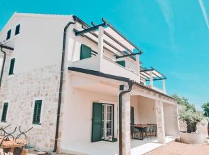 ein weißes Gebäude mit grünen Türen und einem Tisch in der Unterkunft STONE HOUSE JEZERA in Jezera