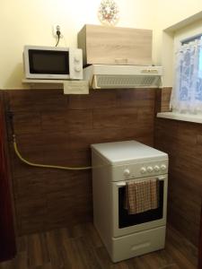 a kitchen with a microwave and a stove at Erdei Vendégház in Nagyesztergár