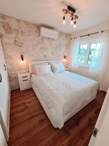 a bedroom with a white bed and a stone wall at STONE HOUSE JEZERA in Jezera