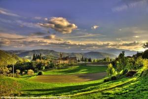 a green field with a church in the distance at Monteombraro Relax in Monte Ombraro