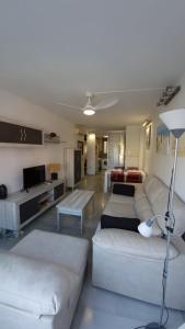 een woonkamer met witte banken en een tv bij Apartamento Denia Elegance Las Marinas in Denia