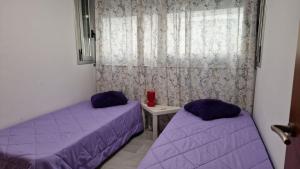 2 bedden in een kamer met paarse lakens en een raam bij Apartamento Denia Elegance Las Marinas in Denia