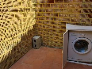 a washing machine in a room with yellow tiled walls at Villa caposchiera a 500 metri dal mare in Villasimius