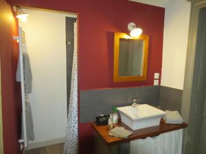a bathroom with a sink and a red wall at Les chambres du Font d'Uzas in Meilhan-sur-Garonne