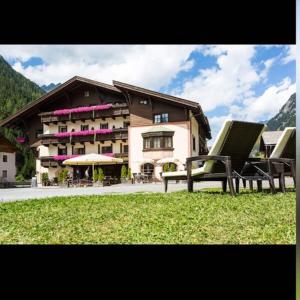 a large building with two benches in front of it at Hotel Restaurant Liesele Sonne in Sankt Leonhard im Pitztal